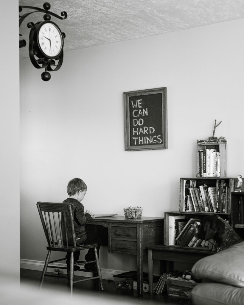 child sitting on chair in front of table doing homework
